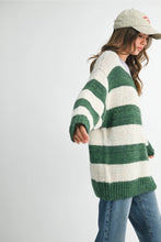 Load image into Gallery viewer, The sweater you’ll live in all season long. This oversized knit features bold forest green stripes and a contrasting lavender neckline for a playful twist. Easy to throw on with jeans or a maxi skirt- cozy, carefree, and totally essential.
